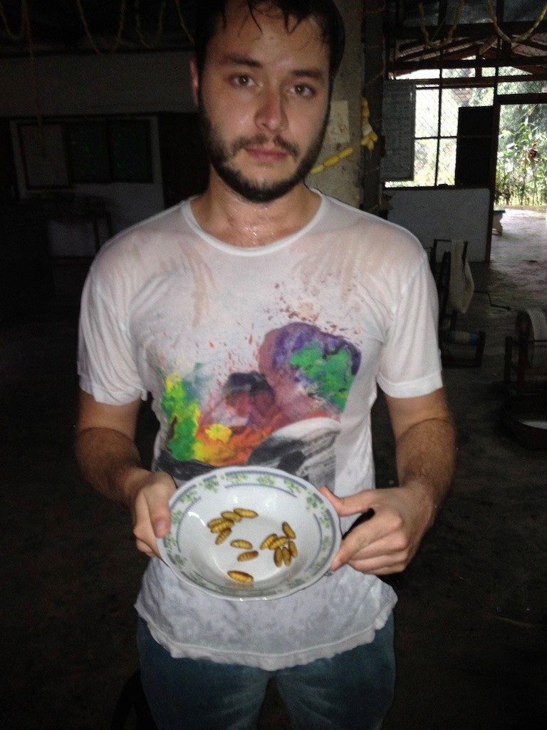 Person in a wet tshirt holding a bowl of larve