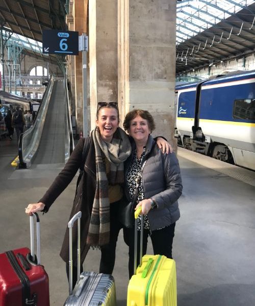 A mother and daughter with suitcases at a train station