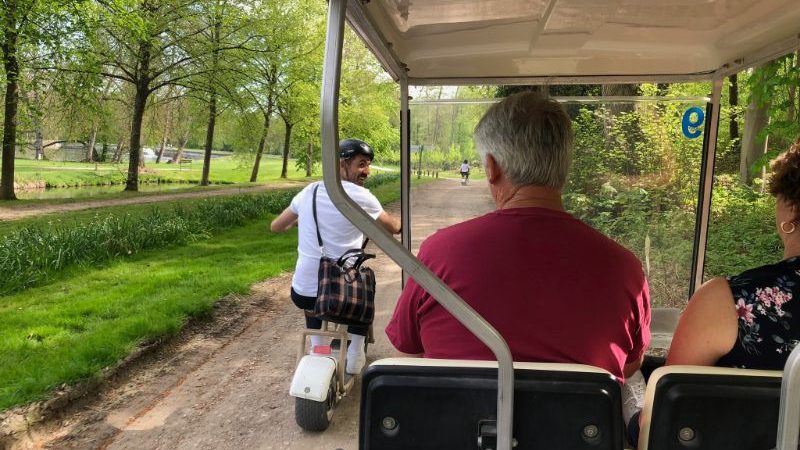 A man riding a bike past a golf buggy