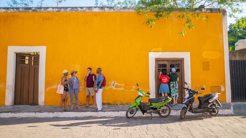 A group of people standing in front of a bright yellow building