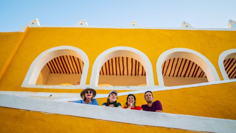 Four people standing on a ramp in front of an old yellow building