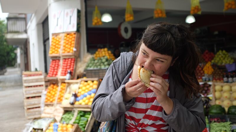 A young woman eating an empanada in Argentina