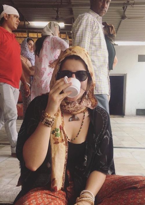 A woman sitting on the ground drinking tea in an Sikh temple