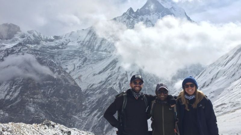 Three people surrounded by mountains in Nepal.