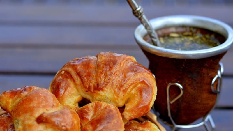 A plate of medialunas alongside a cup of tea