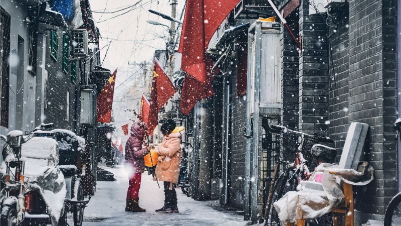 Two people standing in the snow in Beijing