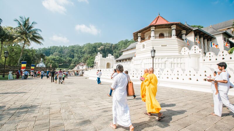 People walking on a path in front of a temple in Sri Lanka