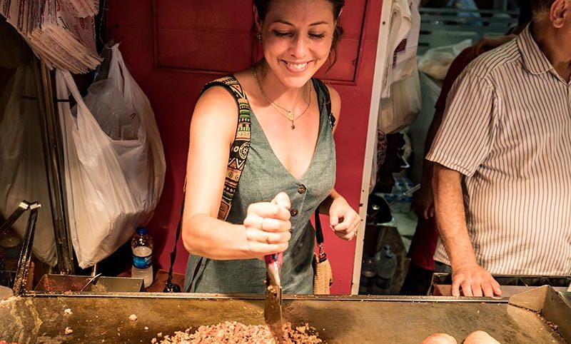 A female traveller cooking a meal in the market