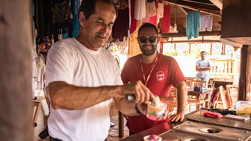 A tour leader watching a man scooping ice cream