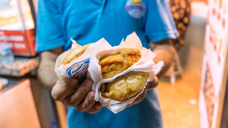 A man holds three burgers up to the camera