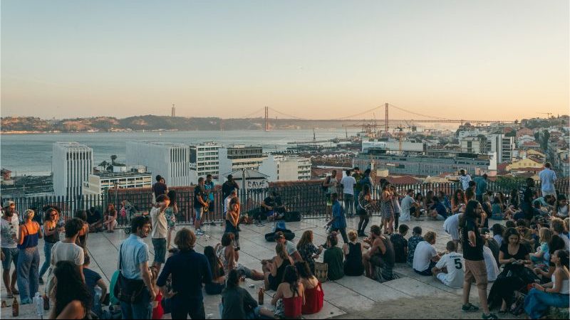 Locals hang out at a viewpoint in Lisbon at sunset