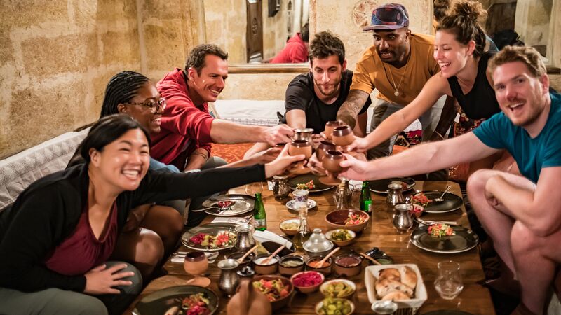 A group of travellers cheersing over dinner in Turkey