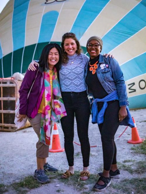 Three women standing in front of a hot air balloon in Turkey