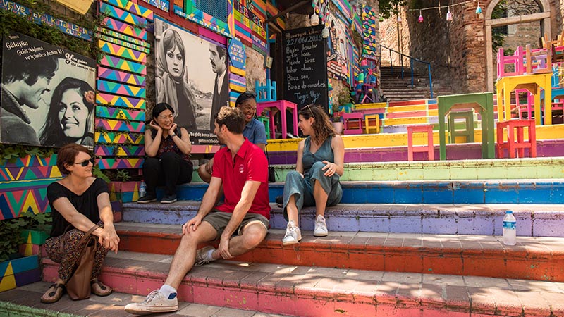Travellers sitting on some brightly painted steps in Balat