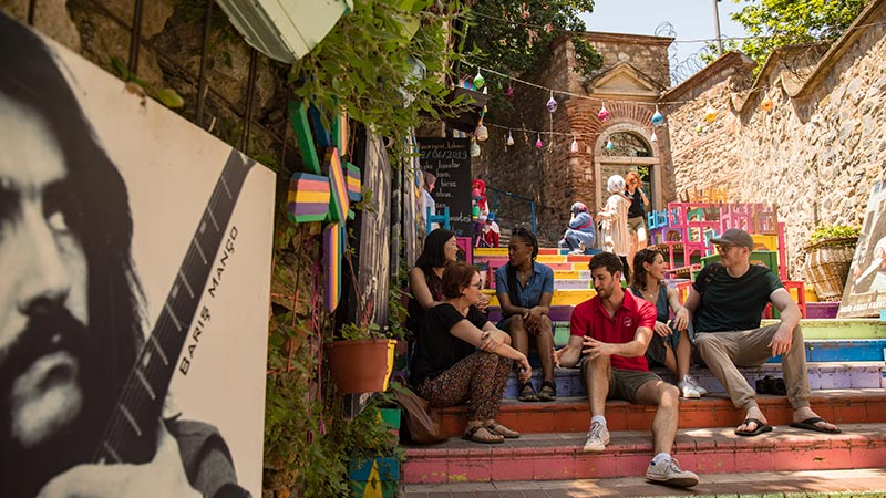 Travellers sitting on colourful steps in Balat, Istanbul.