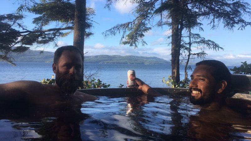 Two men sitting in a hot tub in the Canadian wilderness