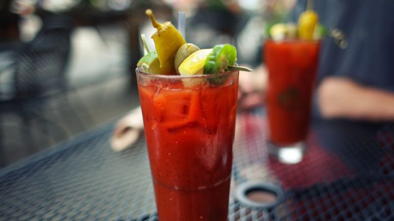 Two tomato juice cocktails on a bar.