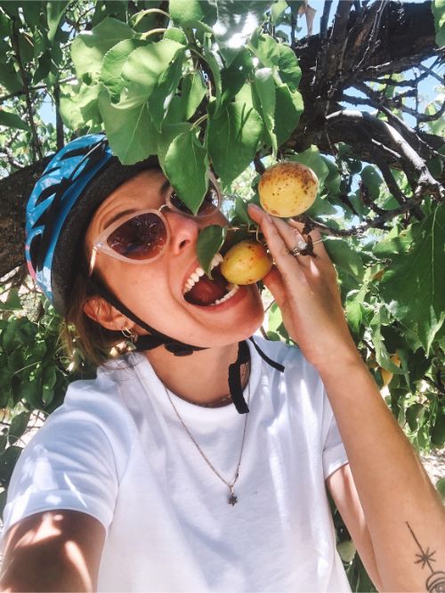 A woman eating an apricot off a tree