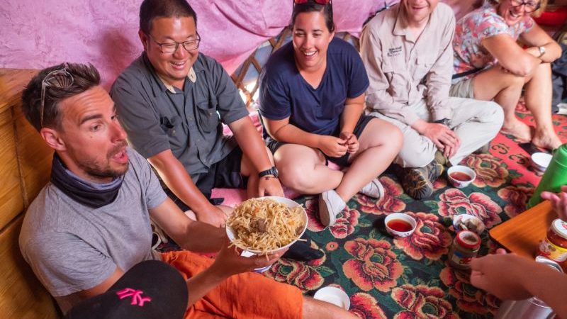 A group of travellers eating on the floor of a ger