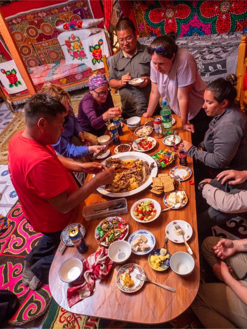 Travelers sitting around a table in a ger, ready for dinner