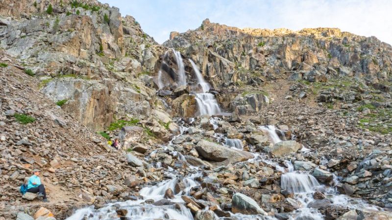 A traveller sitting next to a waterfall in Russia