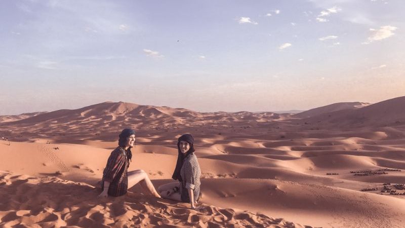 Two girls sitting on a sand dune in Morocco