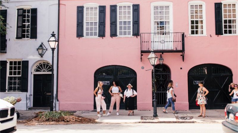 A group of travellers posing outside a pink house