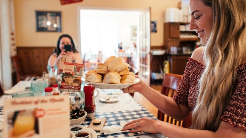 A woman holding a plate of scones in a restaurant