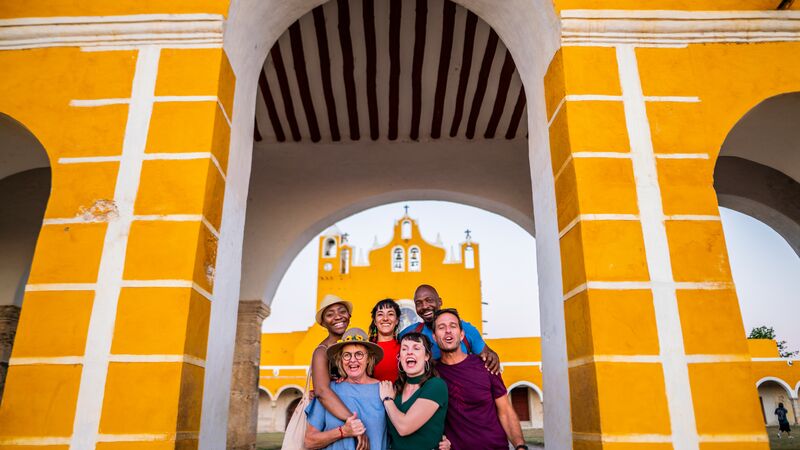 A group of travellers standing in front of a yellow building