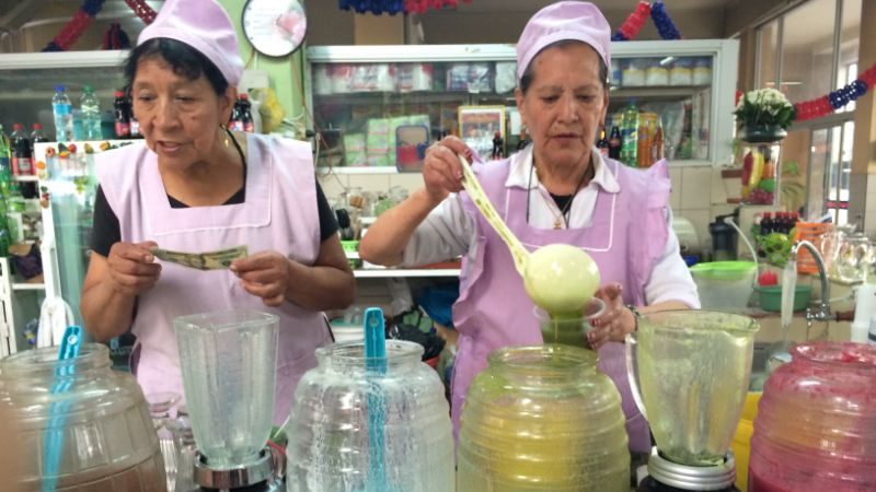 Two women at the Mercado Central spooning juice out of containers