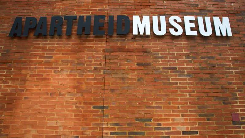 Brick wall with a sign for the Apartheid Museum.