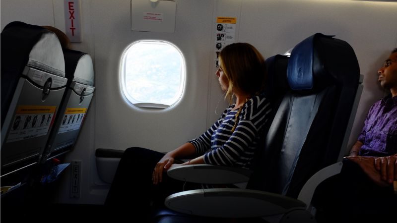 A woman looking out the window of a plane