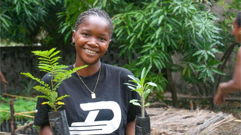 A woman holding two tree saplings