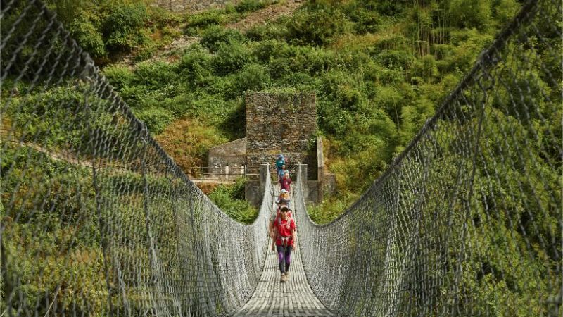 A group of trekkers crossing a suspension bridge.