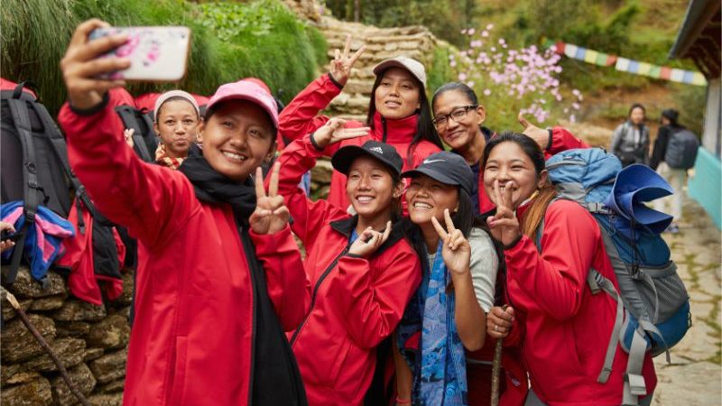 A group of porters wearing red jackets taking a selfie.