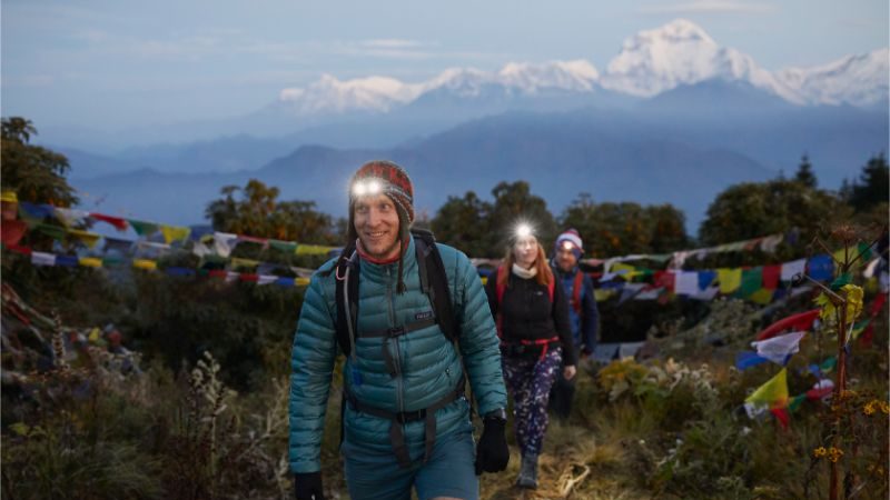 Three hikers wearing head torches at dawn