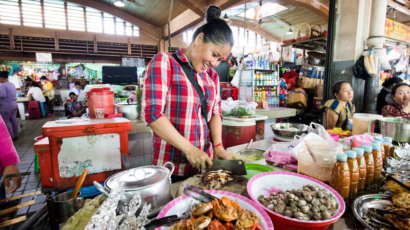 A woman preparing seafood at a market in Cambodia