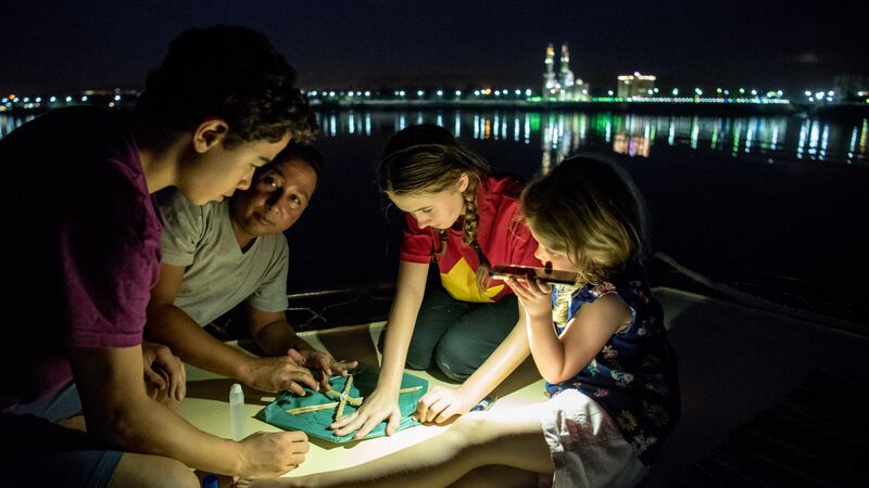 A group of kids making a kite on a boat