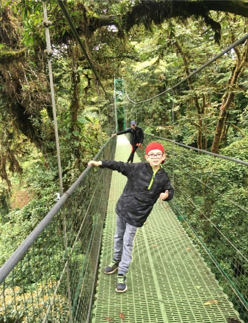 Two boys on a hanging bridge in a jungle