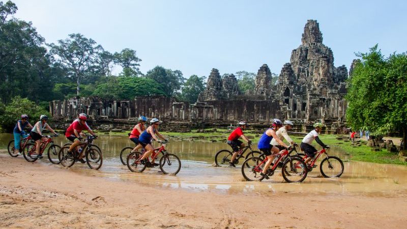 Cyclists riding through Angkor Wat, Cambodia.