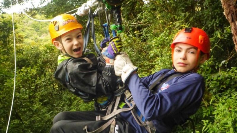 Two boys ziplining in the jungle