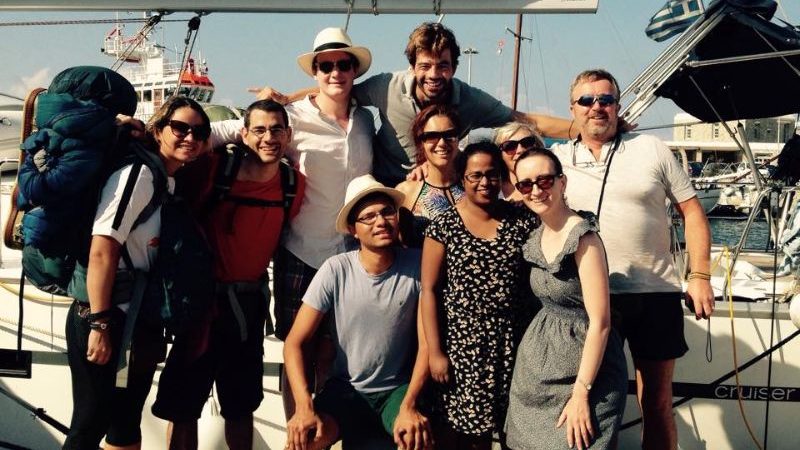 A group of travellers in front of a small boat in Greece