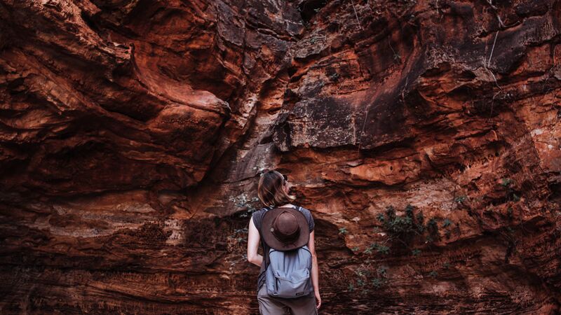 A woman in front of a wall of red rock. 