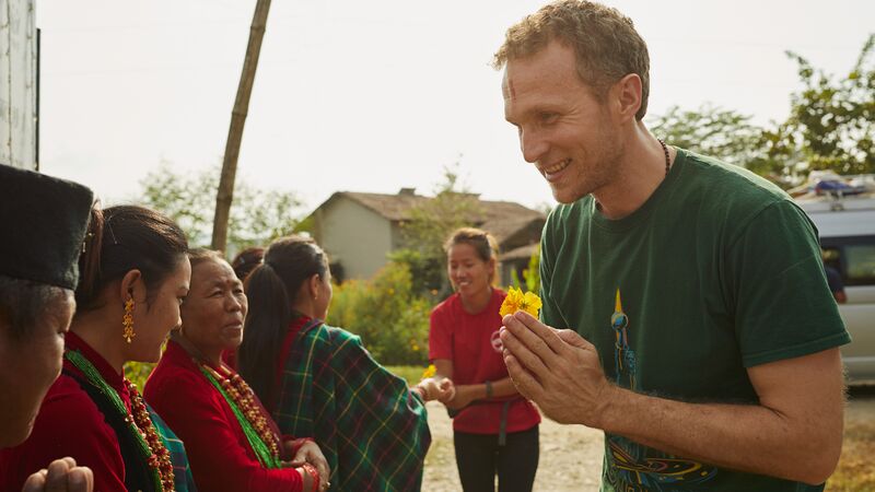 A man being greeted by local women in Nepal