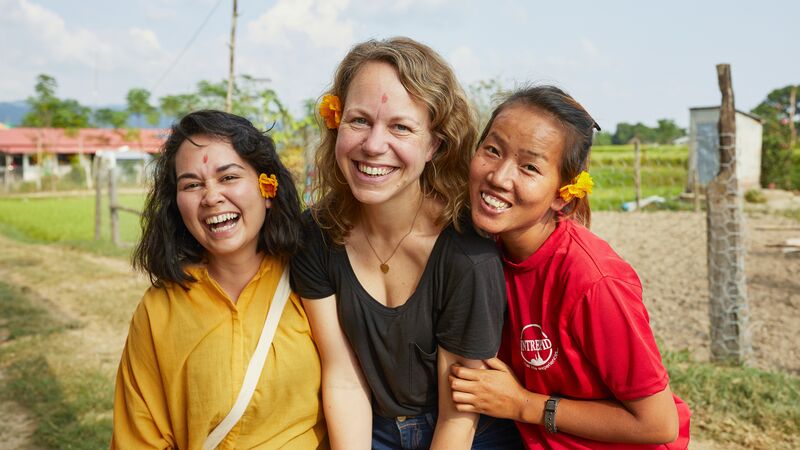 Three smiling women in a small community in Nepal.