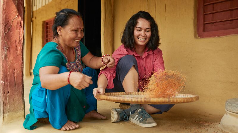 A local woman and traveller split lentils on a basket