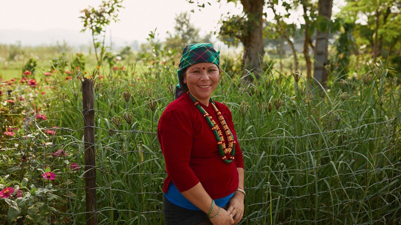 A woman wearing traditional Nepalese dress in front of a field in Nepal