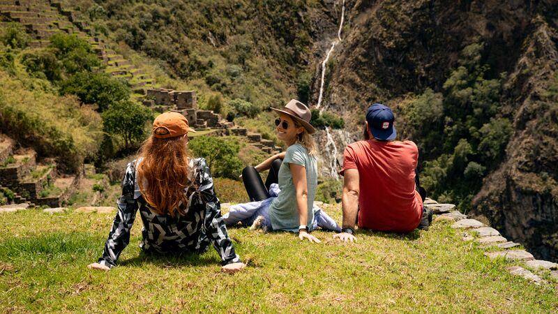 Trekkers sitting on a ledge overlooking Incan ruins in Peru