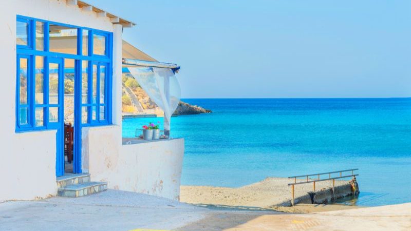 A small white building next to the beach in Syros, the Greek Islands