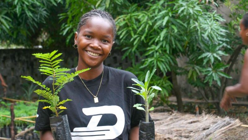 A woman holding two tree saplings in Kenya